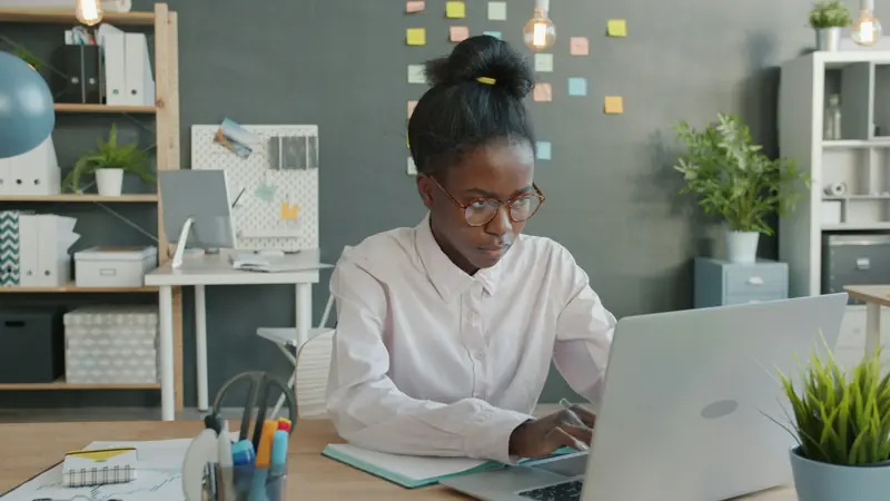 Analyst working on a laptop at a desk in a bright office