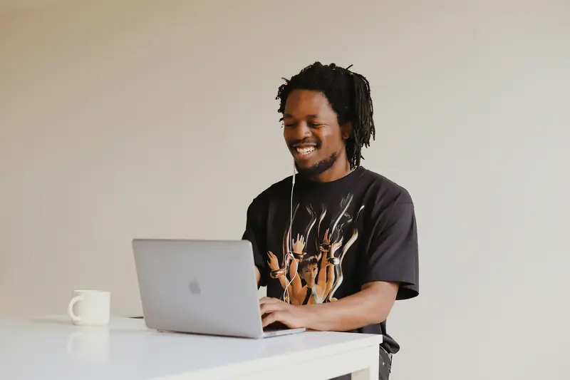 Developer smiling while working on a laptop at a clean white desk