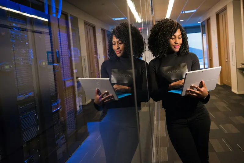 Engineer holding a tablet in a server room next to rows of equipment racks